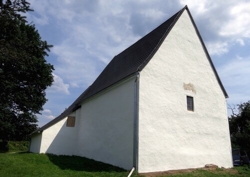 Evanjelický kostolík ukrytý na úpätí kopca za dedinou